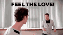 two men are standing in front of a window with the words feel the love written on it
