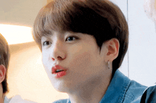 a close up of a person 's face with a denim shirt and earrings