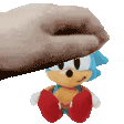 a hand is holding a small stuffed sonic the hedgehog .