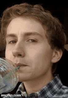 a young man is drinking from a plastic cup with a green straw ..