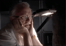 a man wearing glasses and a watch is sitting under a light