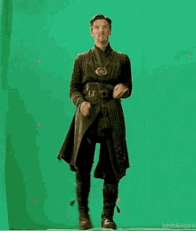 a man in a doctor strange costume is standing in front of a green screen with his arms outstretched .