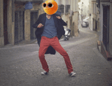 a man with an orange smiley face on his head dancing