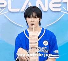 a man in a blue shirt is holding a stack of wooden blocks in his hands .
