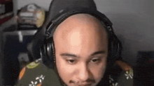a bald man wearing headphones is sitting in front of a computer .