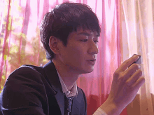 a man in a suit is holding a cell phone in his hand