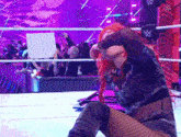 a female wrestler is kneeling down in a wrestling ring .