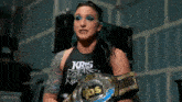 a female wrestler is holding a wrestling championship belt around her waist .
