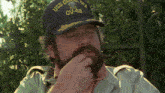 a man with a beard wears a hat that says uss coral sea