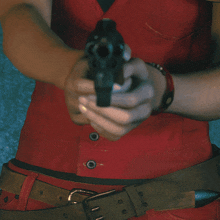a person in a red vest is pointing a gun at the camera