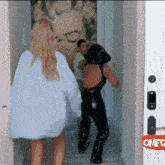 a woman in a white shirt is standing in front of a door that says omfg on it