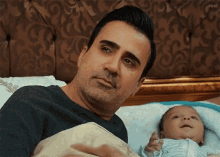 a man laying on a bed holding a baby