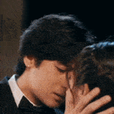 a man in a tuxedo and tie is kissing a woman on the cheek .