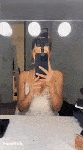 a woman is taking a selfie in front of a mirror while wearing a face mask .