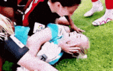 a female soccer player is laying on the grass with her head on someone 's shoulder .