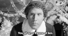 a man is sitting on a throne of lies in front of a christmas tree in a black and white photo .