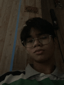 a young man wearing glasses and a striped shirt poses for a picture