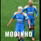 two soccer players are running on a field with the word modinho on the bottom