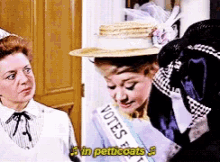 a woman wearing a sash that says " votes in pericoats "