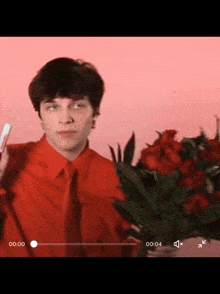 a man in a red shirt and tie is holding a bouquet of flowers