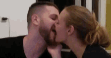 a man and a woman are kissing each other in a room .