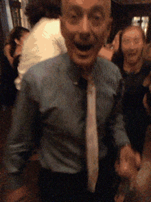 a man in a blue shirt and white tie is dancing