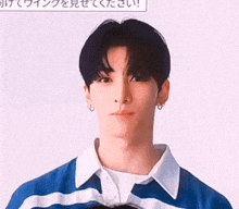 a young man in a blue and white striped shirt is looking at the camera .