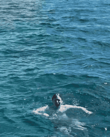 a man is swimming in the ocean with his hands up in the air