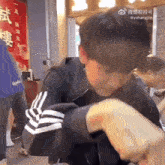 a man in a black and white adidas jacket is eating a piece of food