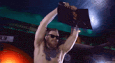 a shirtless man holds up a picture in front of a sign that says " blin "