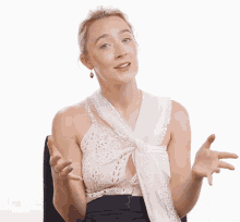 a woman wearing a white lace top is smiling