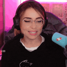 a woman wearing headphones and glasses is smiling in front of a microphone that has a bottle of ketchup on it