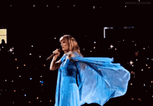 a woman in a long blue dress is dancing on a stage .