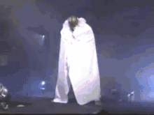 a person in a white cape is standing in the dark