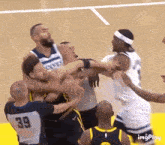 a group of basketball players are fighting each other on a basketball court .