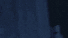 a statue of a man with a sword is in a dark room with a blue background