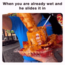 a woman in a blue shirt is holding a tray of nachos and a giant pizza