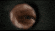 a close up of a person 's eye looking through a hole in a wall