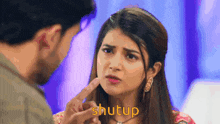 a man is touching a woman 's face with his finger and the word shutup is visible .