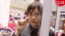 a woman is looking at herself in a mirror in front of a sign that says morgan