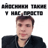 a man wearing ear buds looks at the camera in front of a sign that says ' aiocniki takie '