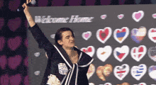 a woman is holding a microphone in front of a welcome home sign