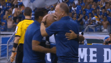a man in a blue shirt is hugging another man in front of a sign that says me i