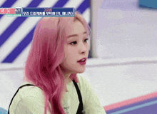 a girl with pink hair is wearing a green shirt that says act