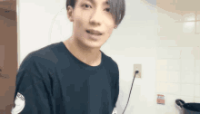 a young man is standing in a kitchen wearing a black t-shirt with the word indigo on it
