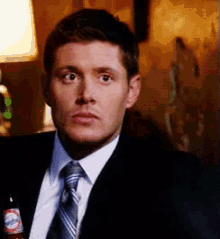 a man in a suit and tie is holding a bottle of coca cola