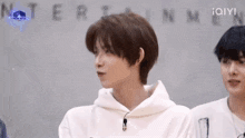 a man with short hair is wearing a white hoodie and standing next to another man .