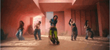 a group of women are dancing in a room with a red wall .