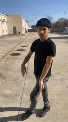 a young man in a black shirt is standing on a concrete sidewalk .