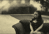 a woman in a corset sits on a couch in front of a swimming pool with the word vevo on the bottom